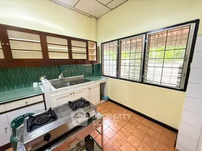 Charming kitchen with gas stove and ample natural light, featuring classic cabinetry and tiled flooring.