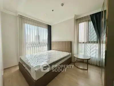 Spacious bedroom with large windows and modern furnishings in a bright apartment.