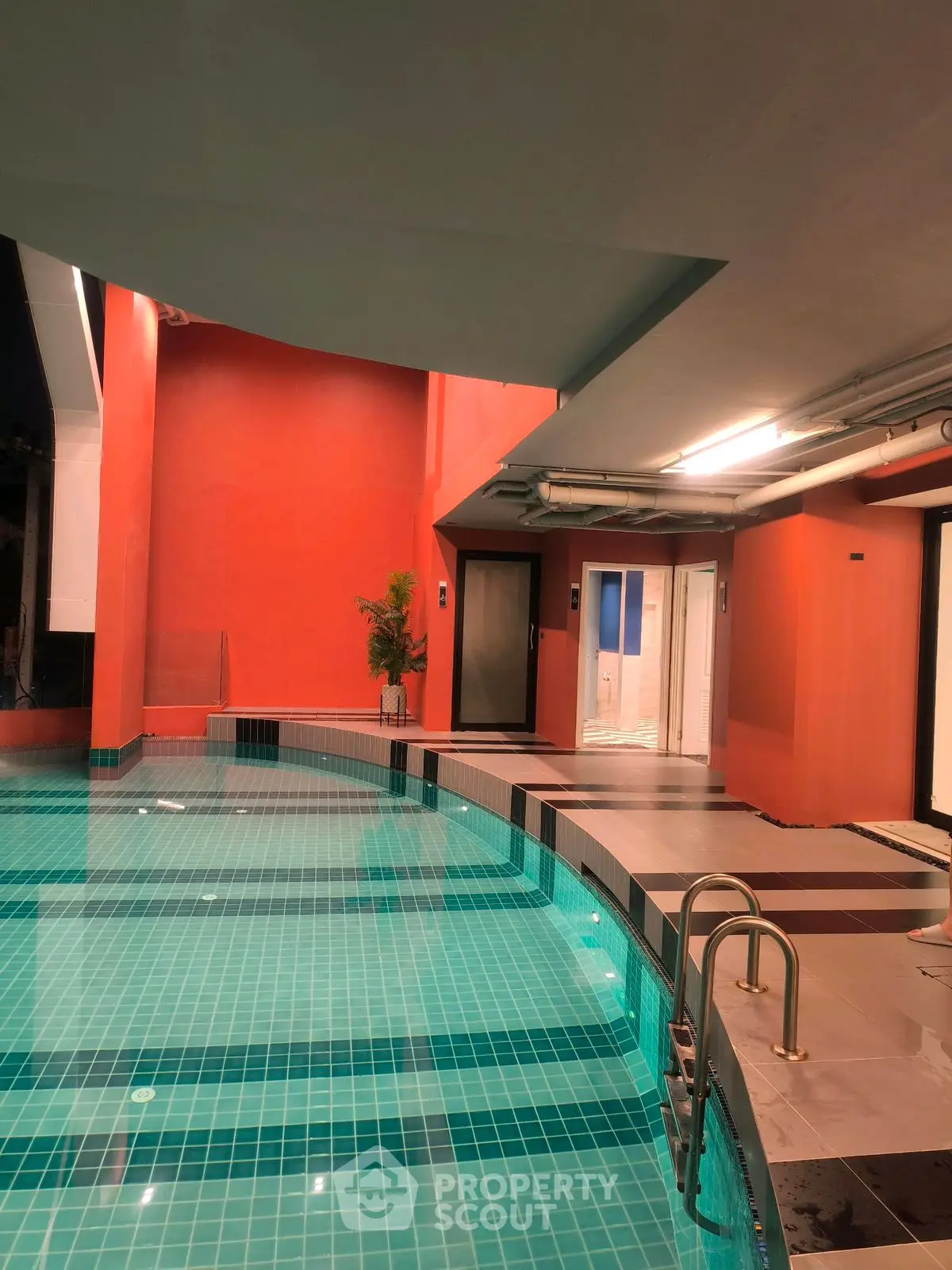 Luxurious indoor pool with modern design and vibrant orange walls, perfect for relaxation.