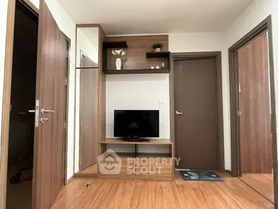 Modern living room with wooden flooring and sleek TV unit in a cozy apartment.