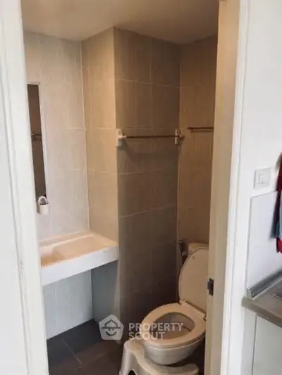 Compact bathroom with modern fixtures and neutral tiles, ideal for small spaces.