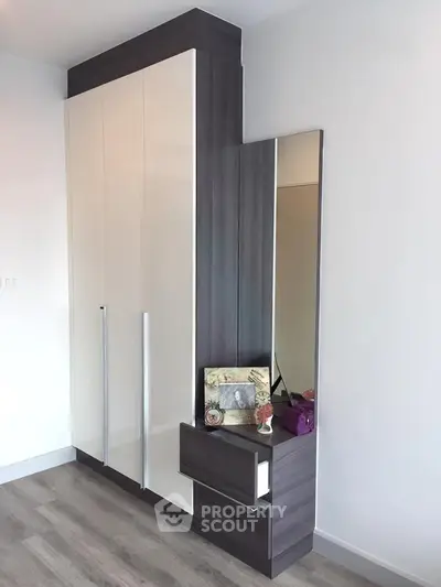 Modern bedroom with sleek wardrobe and mirror, featuring elegant decor and ample storage space.