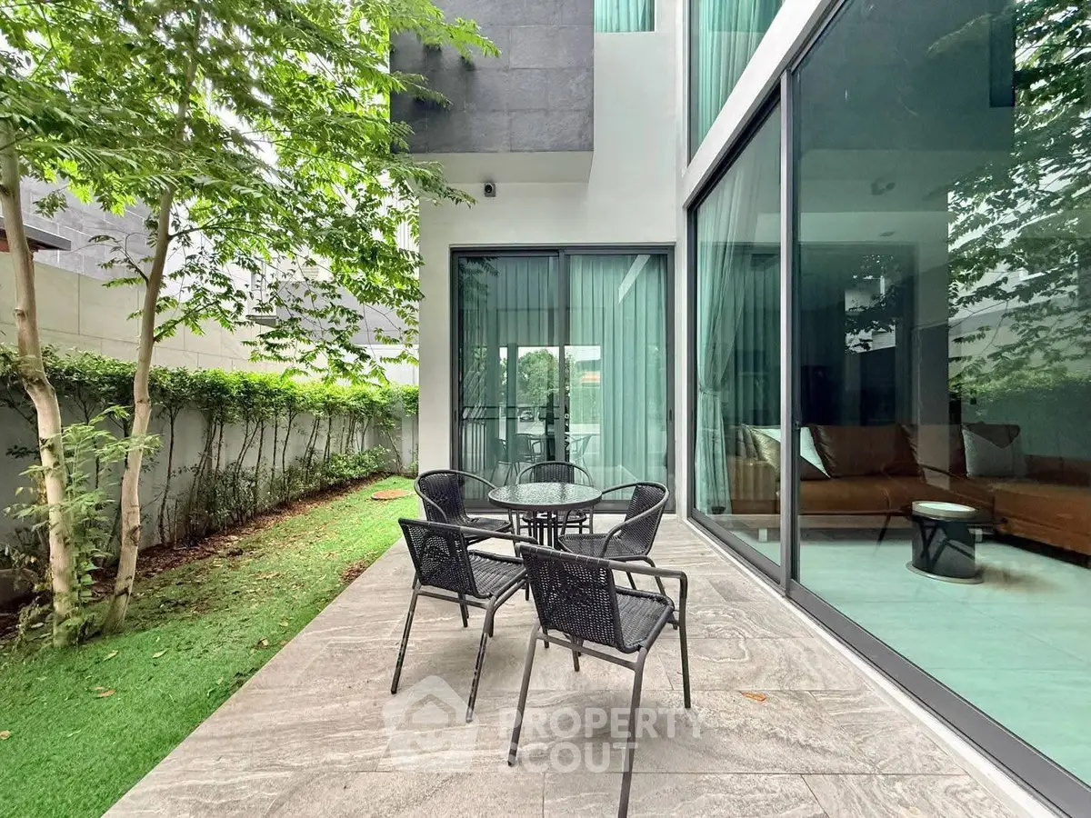 Modern patio with glass doors and outdoor seating in a lush garden setting.