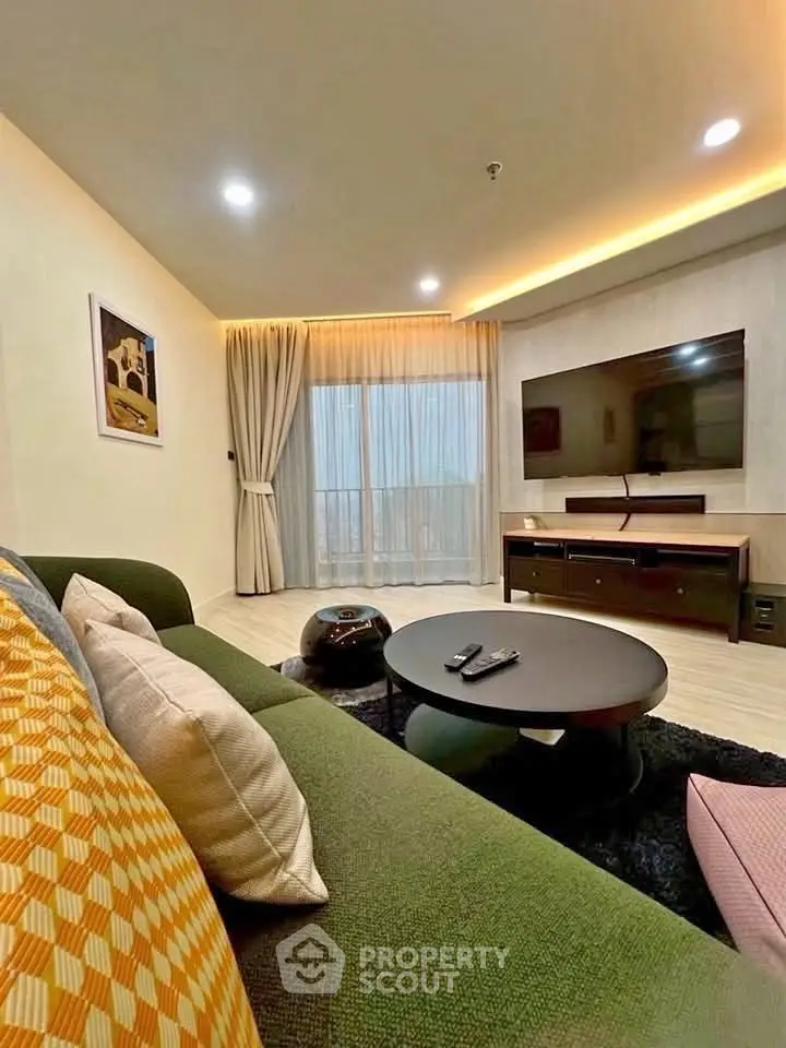 Modern living room with stylish decor, large TV, and cozy seating area.