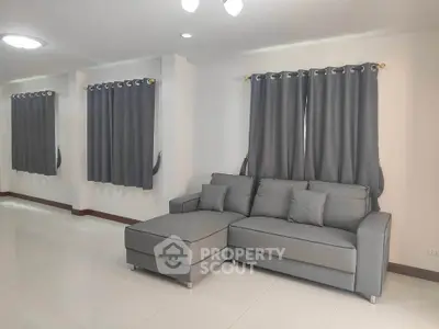 Spacious modern living room with sleek gray sofa and elegant curtains