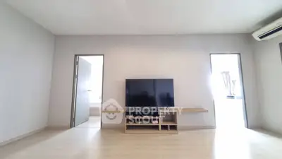 Spacious living room with modern TV setup and minimalist design, perfect for relaxation and entertainment.