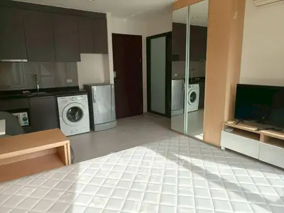 Modern studio apartment with kitchen and appliances, featuring a washing machine and mirrored wardrobe.