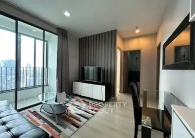 Modern living room with city view, stylish decor, and glass balcony doors in a high-rise apartment.
