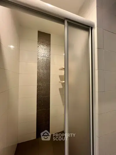 Modern bathroom shower with sleek sliding glass door and stylish tile accent wall.