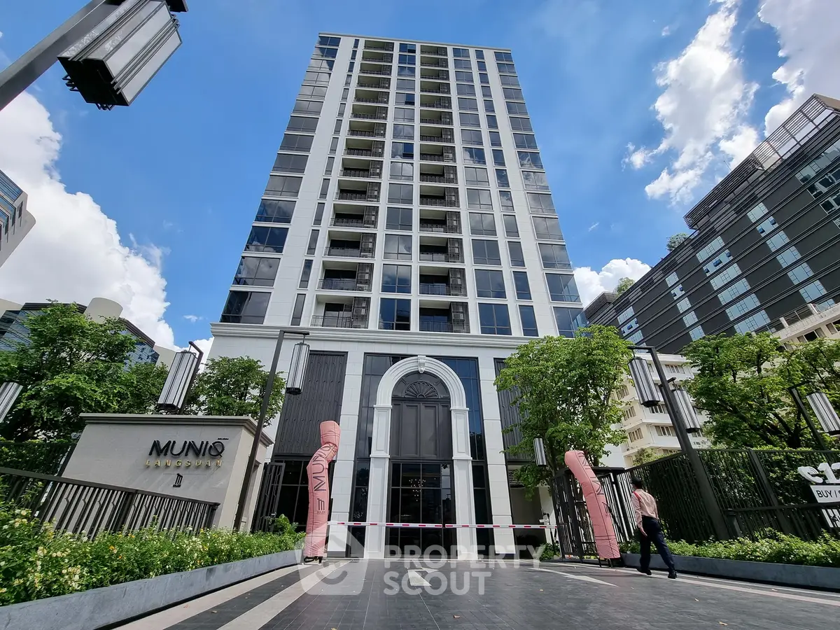 Modern high-rise building with elegant entrance and lush greenery