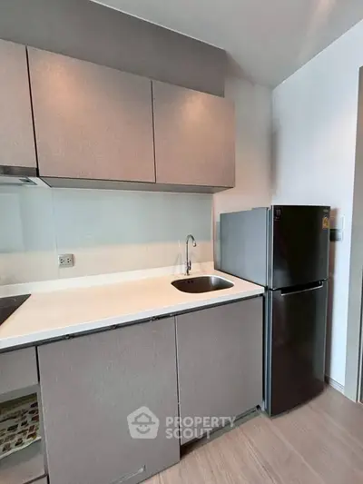 Modern kitchen with sleek cabinets and compact fridge in a stylish apartment.