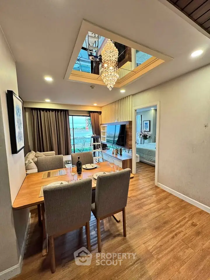 Elegant dining and living area with modern decor and chandelier, featuring a cozy ambiance and wooden flooring.