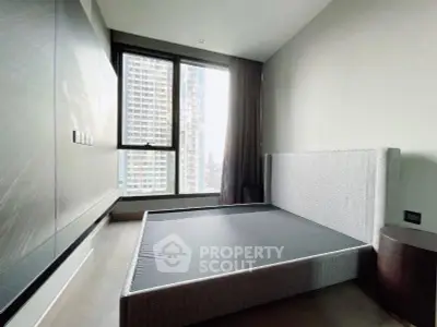 Modern bedroom with large window and city view in high-rise apartment
