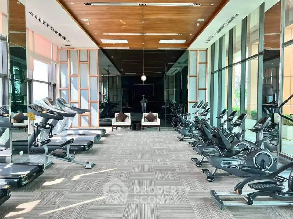 Spacious modern gym with state-of-the-art equipment and large windows for natural light.