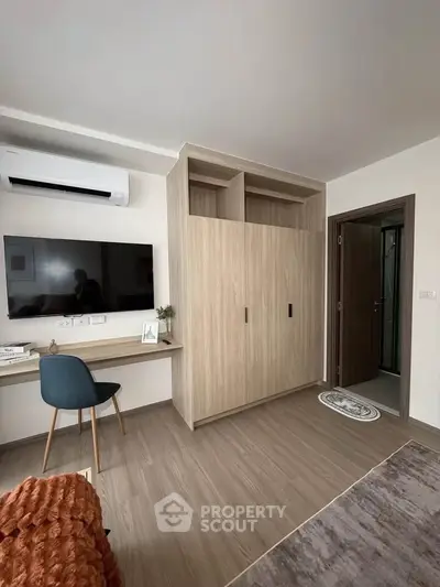 Modern bedroom with sleek wardrobe, wall-mounted TV, and stylish workspace.