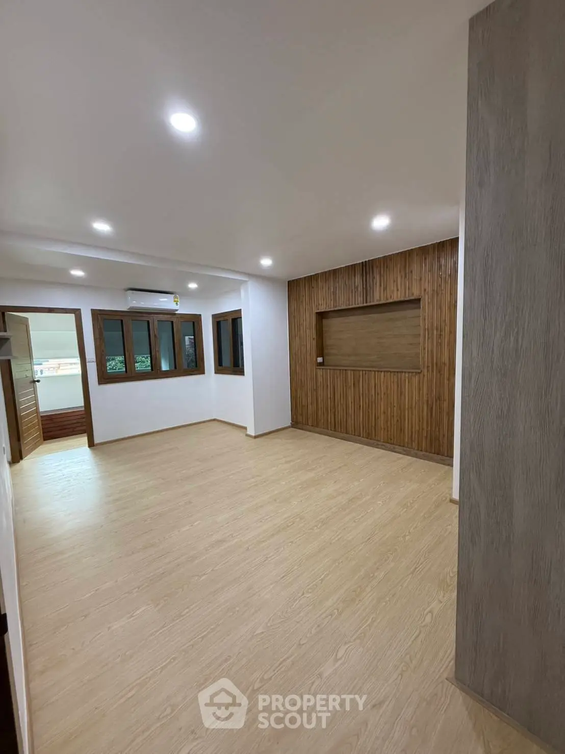 Spacious modern living room with wooden flooring and accent wall, perfect for family gatherings.