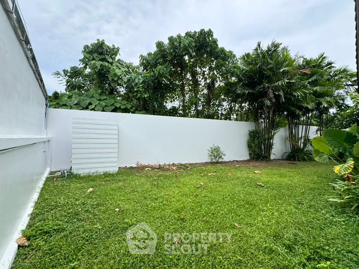 Spacious backyard with lush greenery and privacy fence, perfect for outdoor activities.