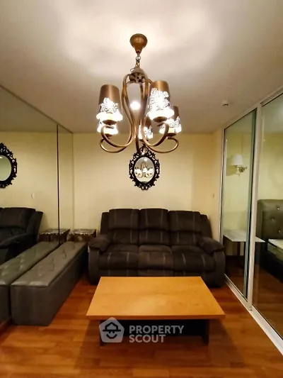 Elegant living room with leather sofa, mirrored wall, and stylish chandelier