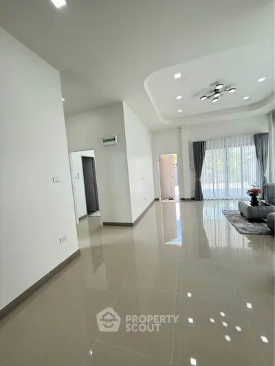 Spacious modern living room with glossy tiled floors and large windows for natural light.