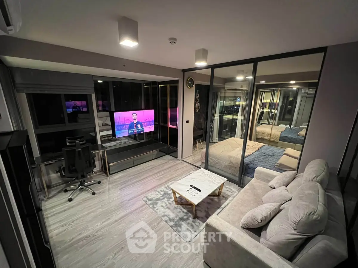 Modern open-plan living room with glass partition and cozy bedroom view