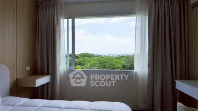 Bright bedroom with large window offering stunning green view.
