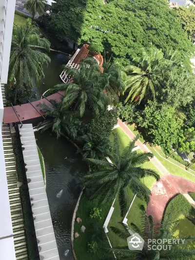 Stunning aerial view of lush garden with palm trees and winding pathways in a luxury residential complex.