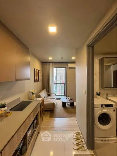 Modern apartment interior with open kitchen and cozy living area, featuring a washing machine and stylish decor.