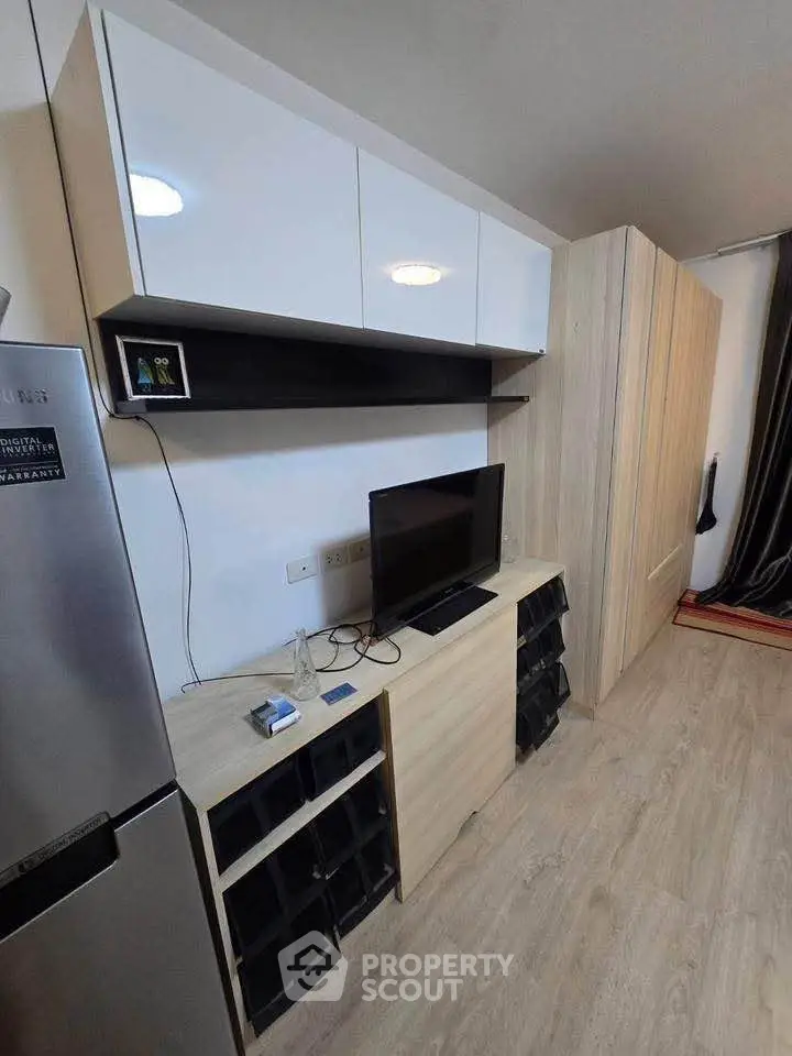 Modern living room with sleek cabinetry and flat-screen TV, featuring stylish wood flooring.