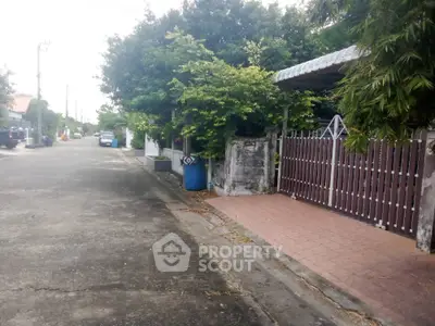 Charming suburban street with lush greenery and gated driveway entrance