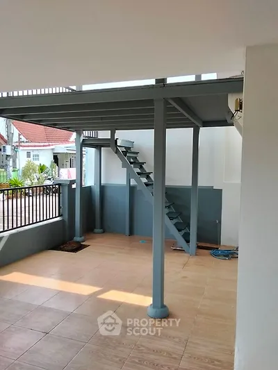 Spacious covered outdoor area with modern staircase and tiled flooring.