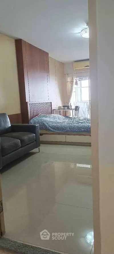Cozy bedroom with modern decor and natural light, featuring a comfortable bed and stylish sofa.
