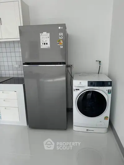 Modern kitchen with sleek fridge and washing machine, perfect for urban living.
