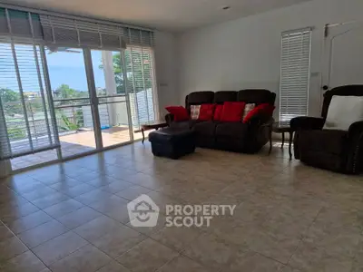 Spacious living room with large windows and balcony access, perfect for relaxation and entertaining.