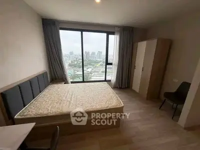 Modern bedroom with large window offering stunning city view, featuring minimalist furniture and natural light.