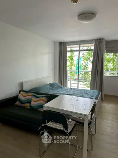 Cozy studio apartment with modern furnishings and large window for natural light.