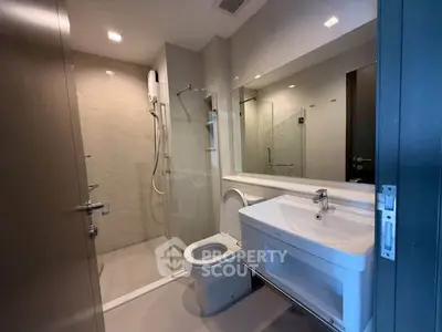 Modern bathroom with glass shower and sleek fixtures in contemporary apartment.
