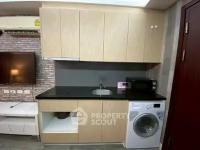Modern kitchen with washing machine and microwave, sleek cabinetry, and stylish backsplash.