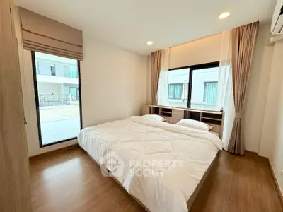 Cozy bedroom with large windows and modern decor in a stylish apartment.