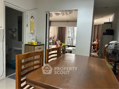Spacious dining area with wooden table and chairs, adjacent to a cozy living room with natural light.