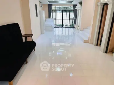 Spacious open-plan living area with glossy white tiles and large windows for natural light.