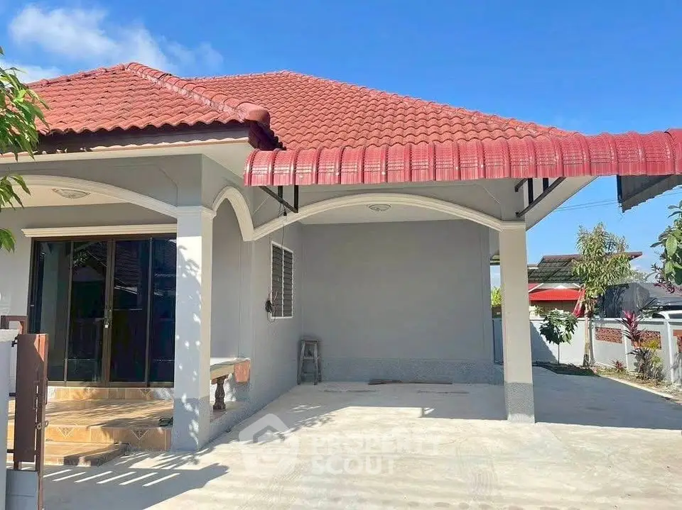 Charming single-story home with red-tiled roof and spacious driveway, perfect for family living.