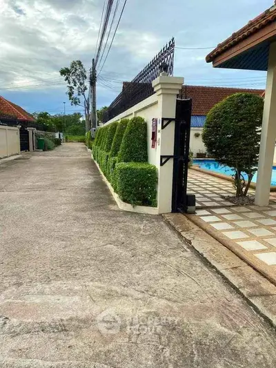 Charming residential entrance with lush greenery and poolside view