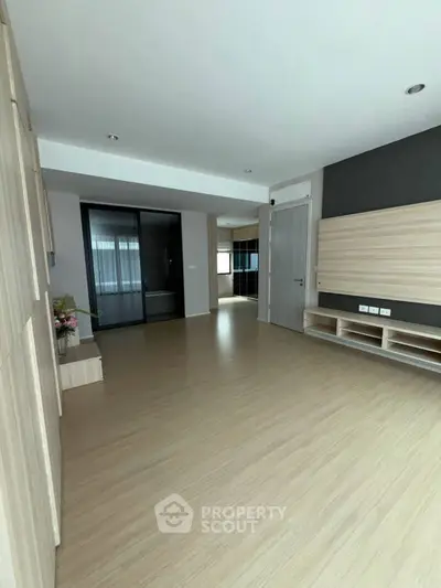Spacious modern living room with wooden flooring and built-in storage solutions.