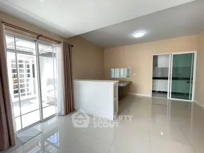 Spacious open-plan living area with sliding glass doors and modern kitchen