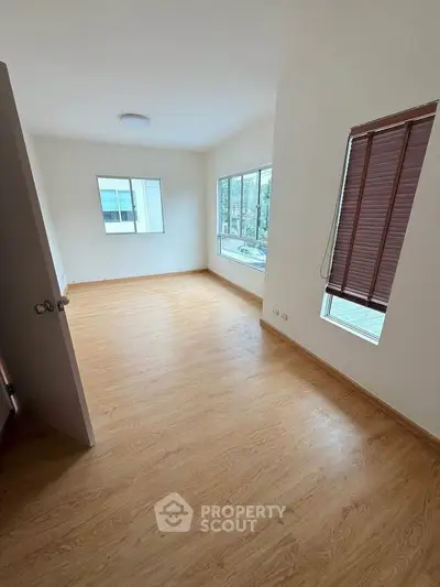 Spacious empty room with large windows and wooden flooring, perfect for customization.