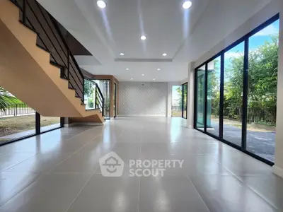 Spacious modern living room with large windows and elegant staircase