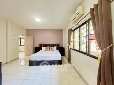 Spacious bedroom with large windows and modern decor in a bright home.