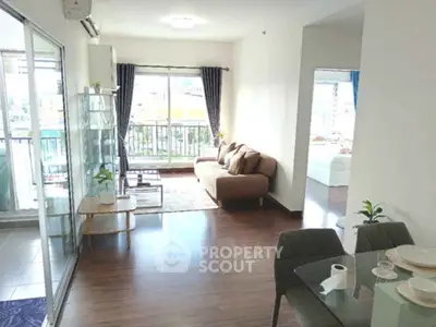 Spacious living room with modern decor and large windows offering natural light and balcony access.