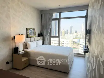 Modern bedroom with city view, large window, and stylish decor in high-rise apartment.