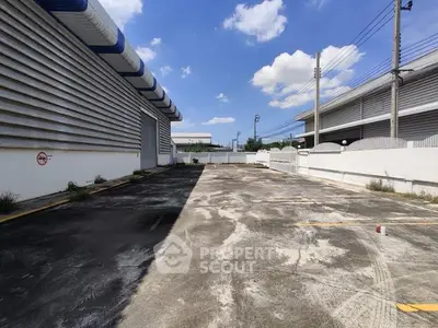 Spacious industrial warehouse exterior with ample parking space under clear blue sky.